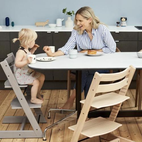 Niño usando la Tripp Trapp como silla evolutiva, sentado cómodamente junto a la familia en la mesa del comedor